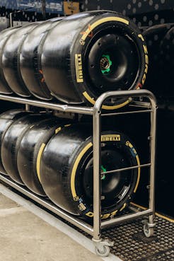 Close-up of Pirelli racing tires stacked on a metal rack in a garage setting.